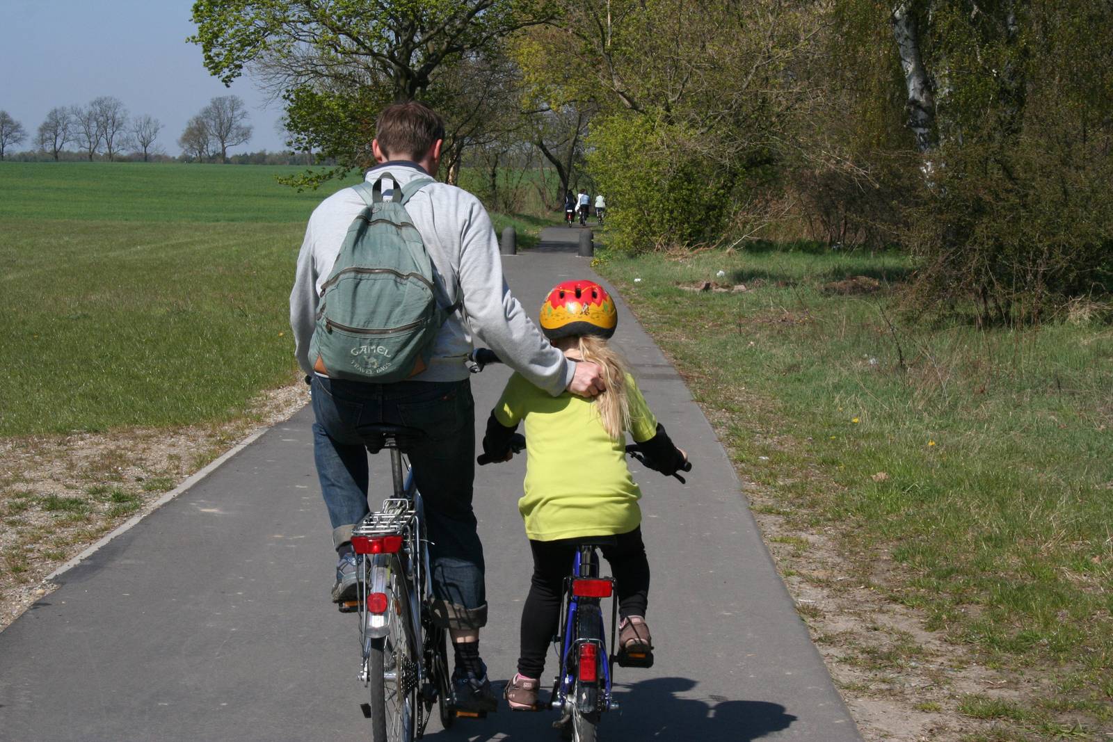 Vater und Kind radeln einen asphaltierten Radweg entlang