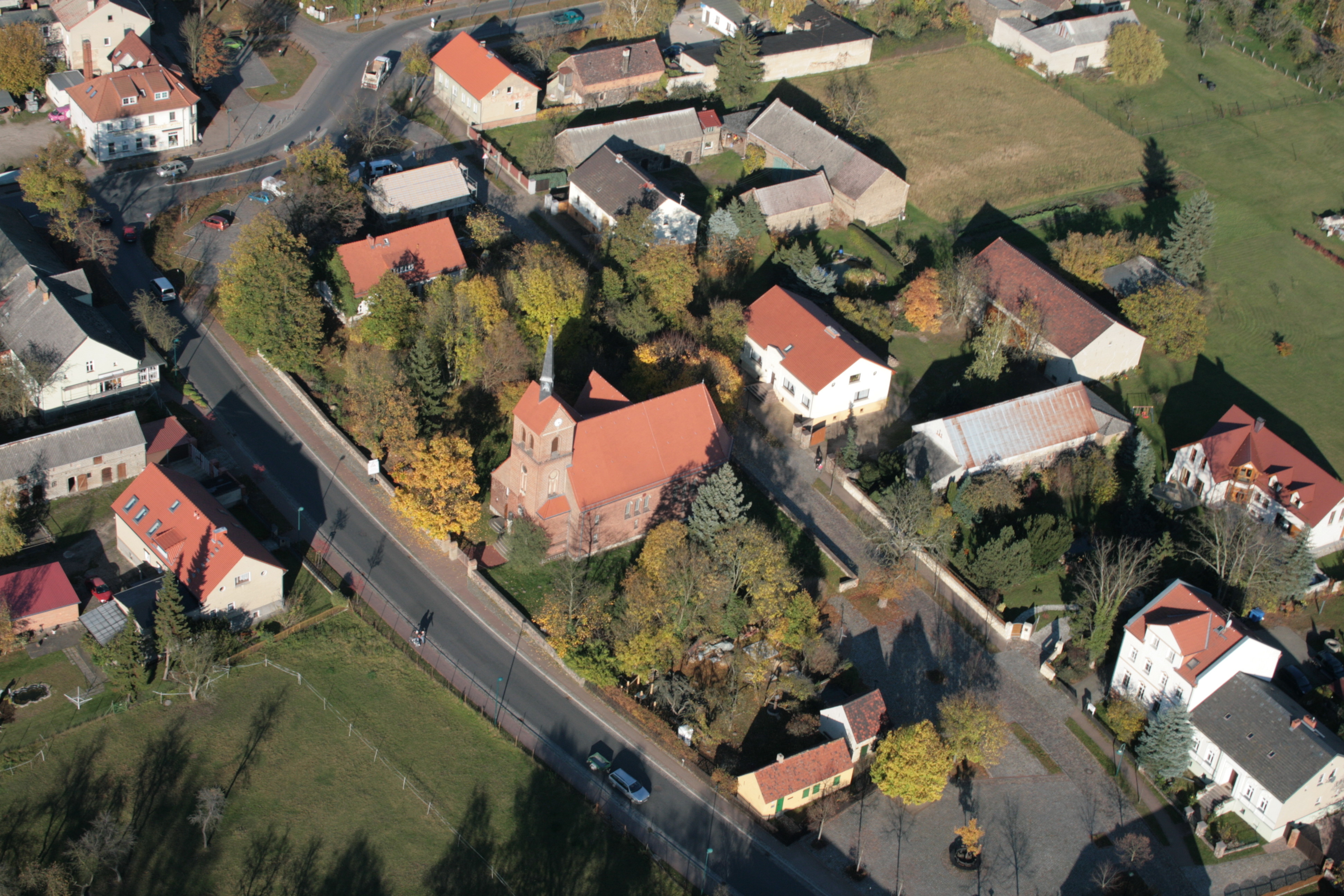 Der historische Dorfanger aus der Vogelperspektive aufgenommen mit Kirche, Büdnerhaus und Angerscheune.